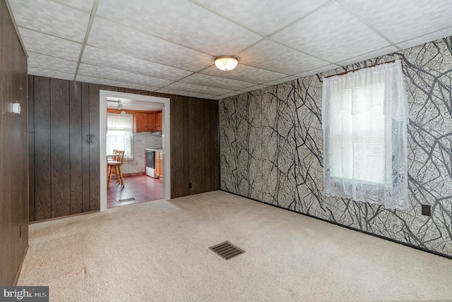 carpeted spare room featuring wood walls