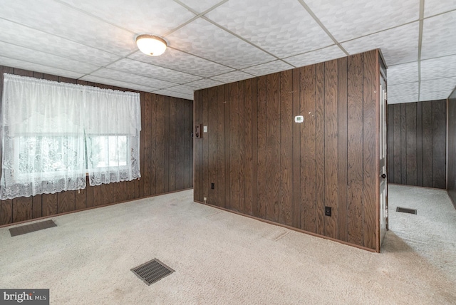 carpeted spare room with wood walls