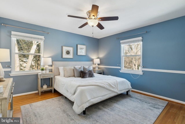 bedroom featuring multiple windows, hardwood / wood-style flooring, and ceiling fan