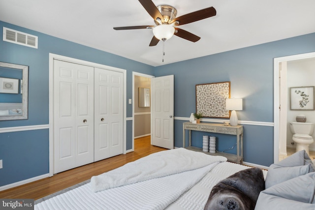 bedroom with hardwood / wood-style flooring, ensuite bathroom, ceiling fan, and a closet