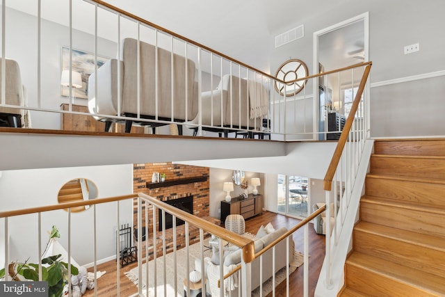 stairway featuring a brick fireplace and wood-type flooring