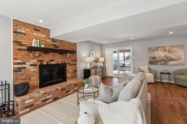 living room with dark hardwood / wood-style flooring and a brick fireplace