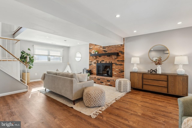 living room featuring wood-type flooring and a brick fireplace