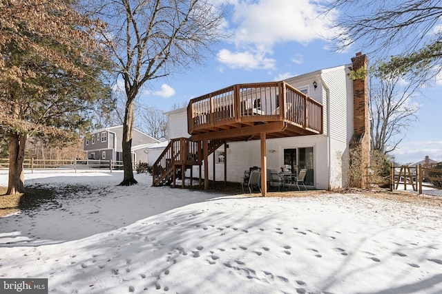 snow covered back of property with a deck