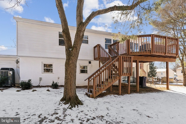 snow covered house with a wooden deck and central air condition unit