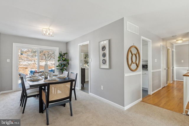 dining room featuring light carpet and a notable chandelier