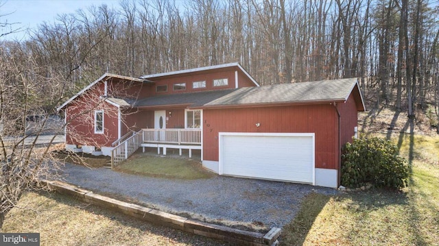 view of front facade with a shingled roof, covered porch, and driveway