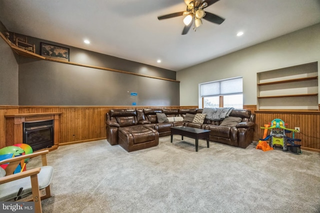 living room featuring ceiling fan, light colored carpet, and wooden walls