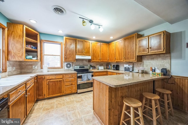 kitchen featuring dishwasher, kitchen peninsula, double oven range, sink, and a kitchen bar