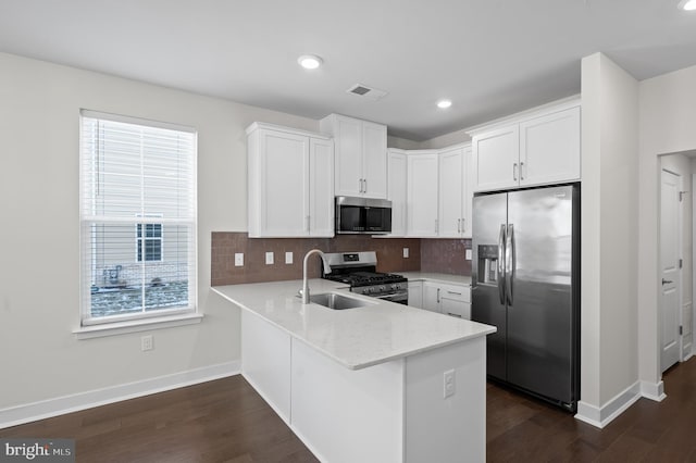 kitchen with decorative backsplash, white cabinets, appliances with stainless steel finishes, and kitchen peninsula