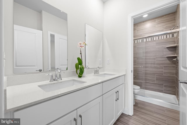 bathroom with toilet, vanity, and tiled shower