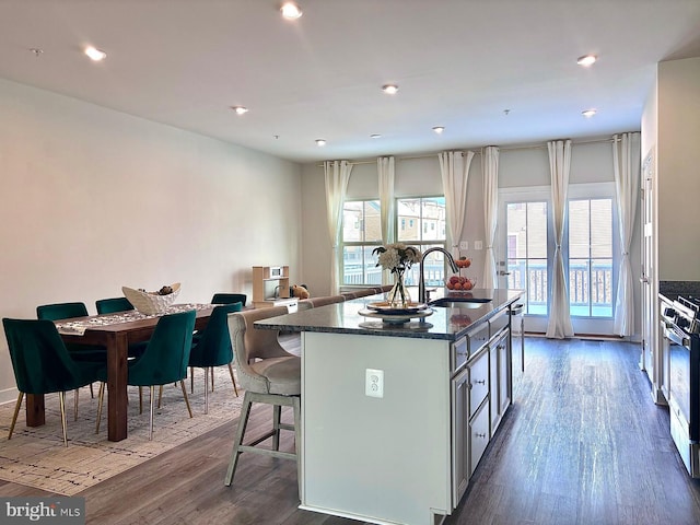 kitchen featuring a center island, sink, stainless steel stove, dark hardwood / wood-style floors, and a breakfast bar area