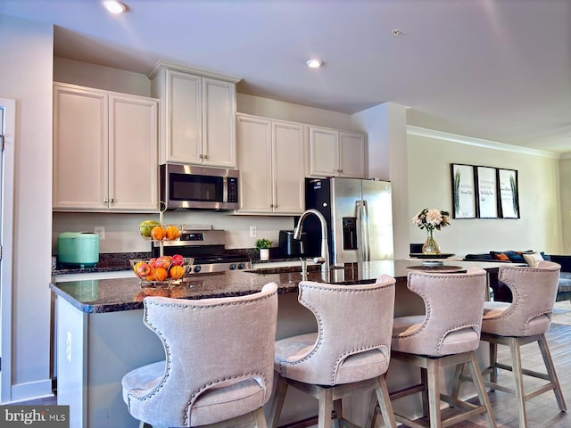 kitchen featuring stainless steel appliances, white cabinets, and a kitchen island with sink