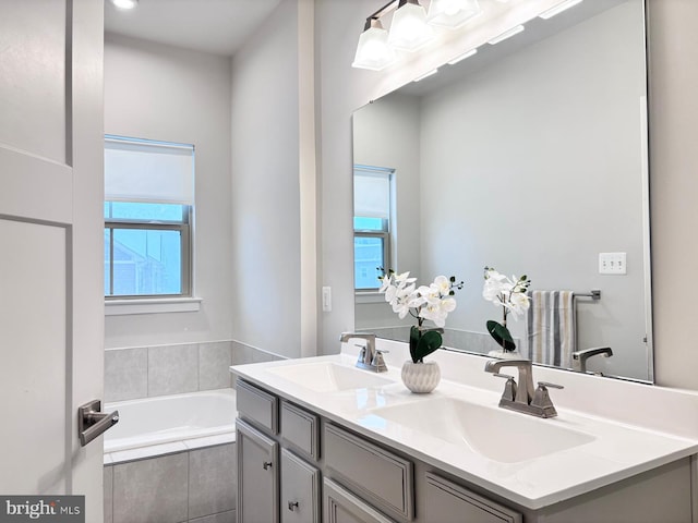 bathroom with tiled tub and vanity