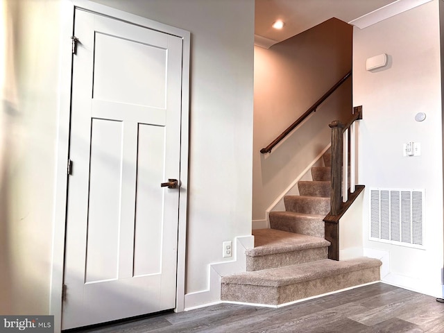 staircase with crown molding and wood-type flooring