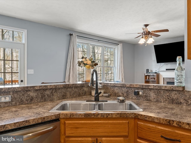 kitchen with stainless steel dishwasher, a tile fireplace, sink, and a textured ceiling