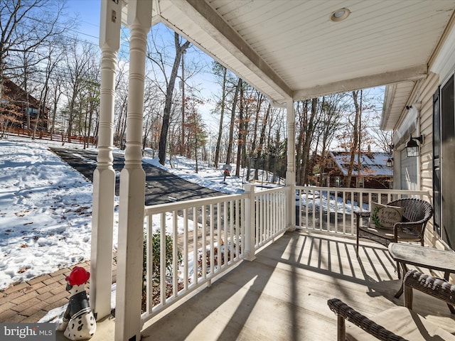 snow covered back of property with a porch