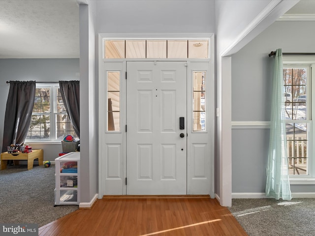 entryway with crown molding and carpet floors