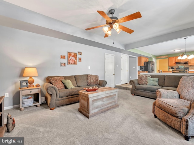 carpeted living room with ceiling fan with notable chandelier