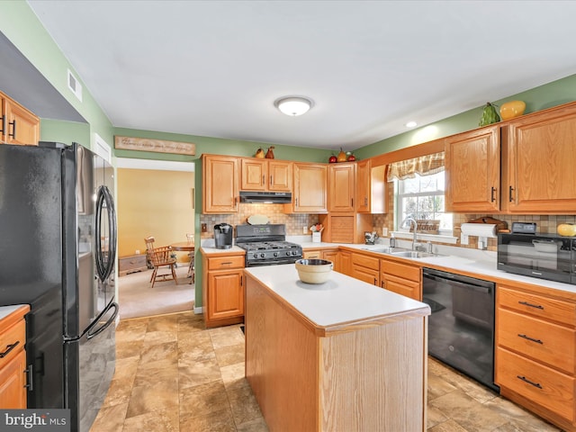 kitchen featuring tasteful backsplash, sink, black appliances, and a center island