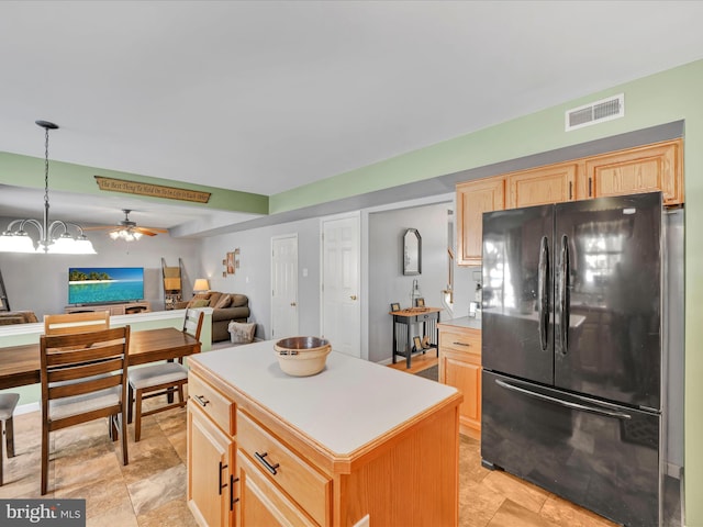 kitchen with black fridge, a center island, hanging light fixtures, light brown cabinets, and ceiling fan with notable chandelier