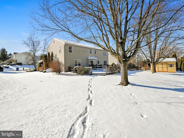 snow covered back of property with a storage shed