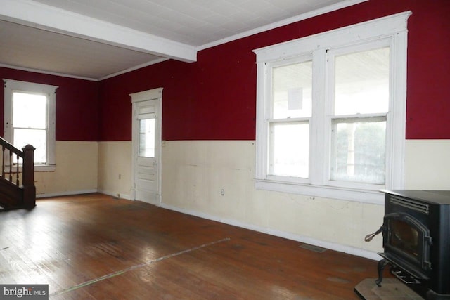 living room featuring crown molding, beam ceiling, a wood stove, and dark hardwood / wood-style floors