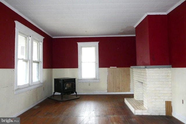 unfurnished living room featuring a wood stove, a wealth of natural light, dark hardwood / wood-style flooring, and crown molding