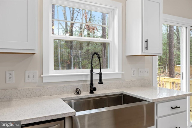 kitchen with light stone countertops, sink, and white cabinets