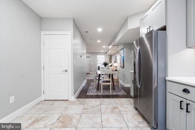 kitchen featuring stainless steel refrigerator with ice dispenser and white cabinetry