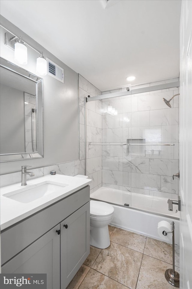 full bathroom with toilet, vanity, tile walls, and shower / bath combination with glass door