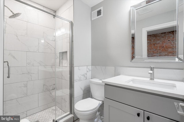 bathroom with a shower with shower door, tile walls, toilet, and vanity