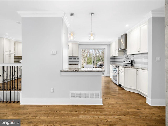 kitchen with light stone counters, white cabinets, range with two ovens, and wall chimney range hood