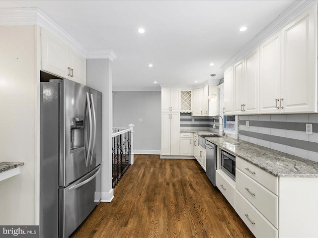 kitchen with appliances with stainless steel finishes, hanging light fixtures, light stone countertops, white cabinets, and decorative backsplash