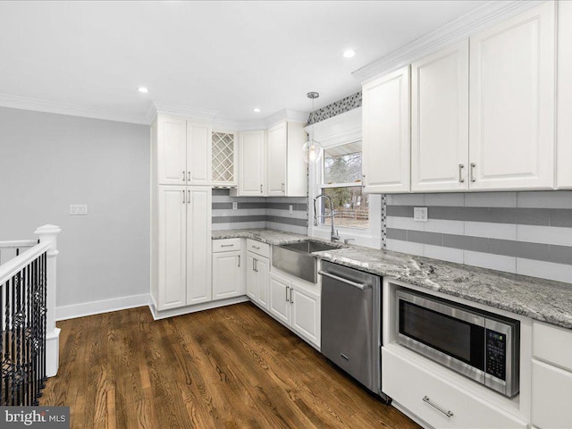 kitchen featuring appliances with stainless steel finishes, decorative light fixtures, white cabinetry, sink, and light stone countertops