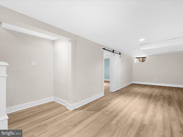 basement featuring a barn door and light hardwood / wood-style floors