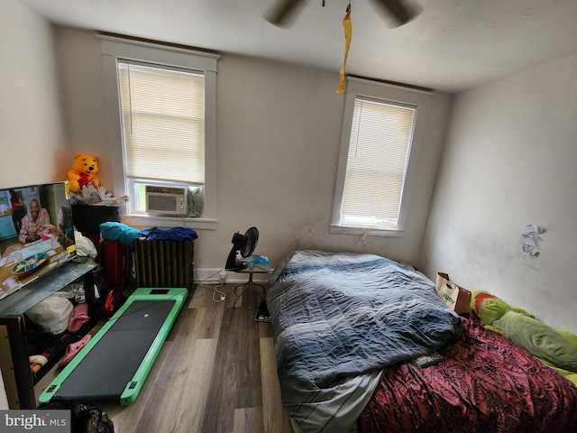 bedroom with ceiling fan, cooling unit, multiple windows, and hardwood / wood-style floors