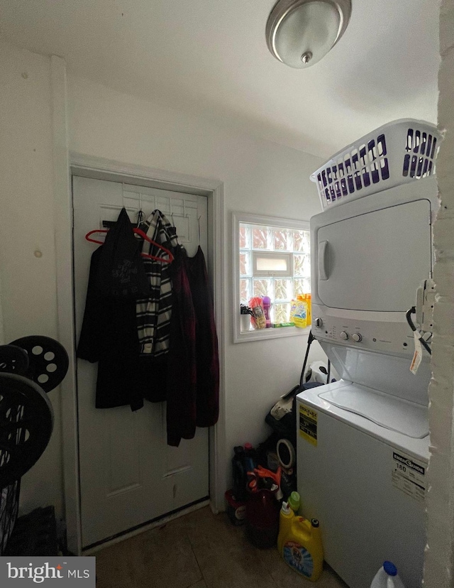 laundry room with tile patterned floors and stacked washer / dryer