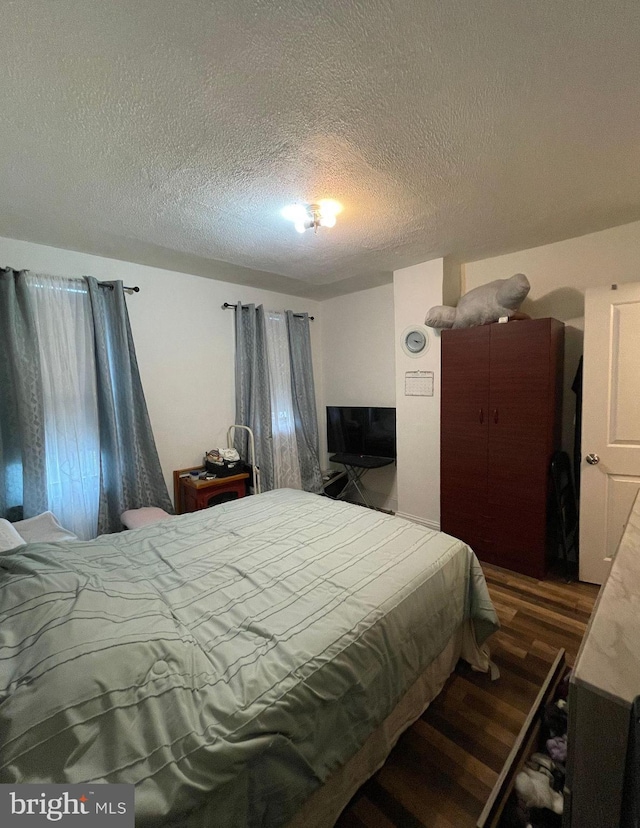 bedroom featuring a textured ceiling and dark hardwood / wood-style flooring