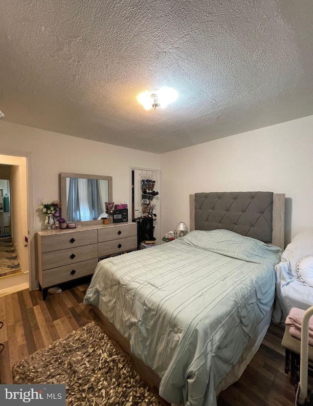 bedroom with dark hardwood / wood-style flooring and a textured ceiling