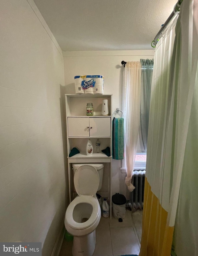 bathroom featuring toilet, radiator, and tile patterned floors