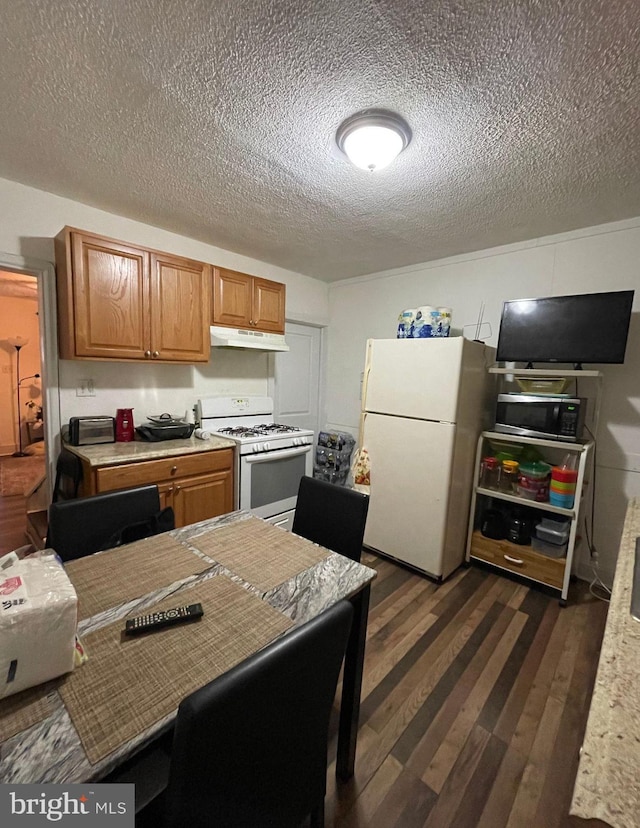 kitchen with dark hardwood / wood-style flooring, white appliances, and a textured ceiling