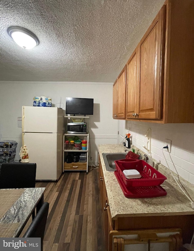 kitchen with dark hardwood / wood-style floors, sink, white fridge, and a textured ceiling