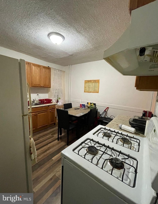 kitchen featuring exhaust hood, a textured ceiling, dark hardwood / wood-style floors, and white appliances