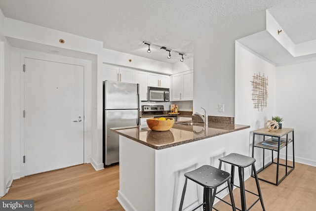 kitchen featuring white cabinetry, sink, kitchen peninsula, stainless steel appliances, and a textured ceiling