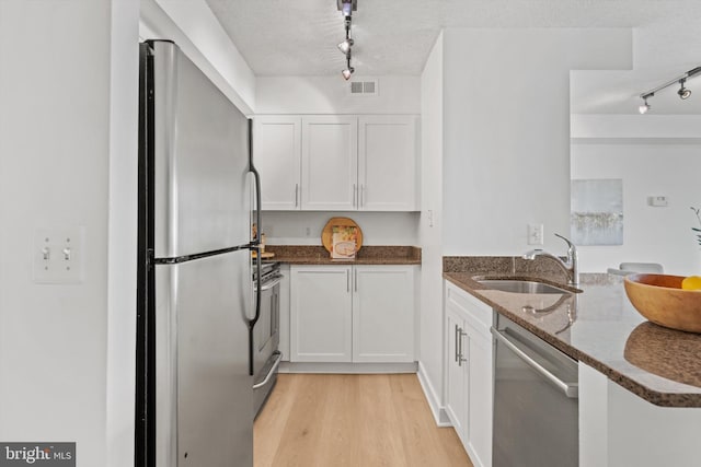 kitchen featuring dark stone countertops, sink, stainless steel appliances, and white cabinets