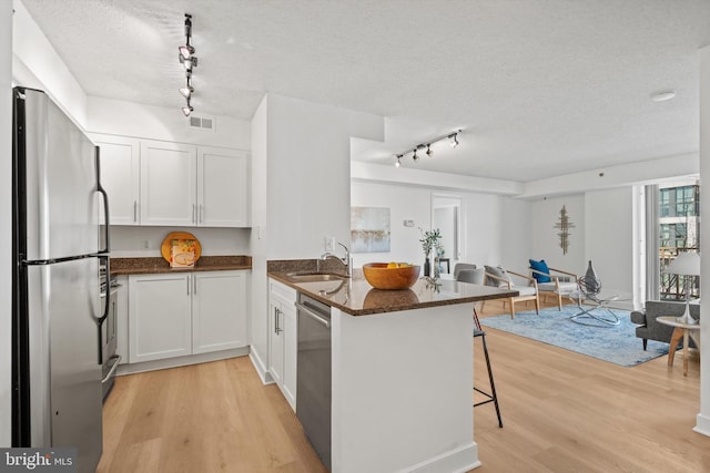 kitchen featuring sink, white cabinetry, appliances with stainless steel finishes, a kitchen breakfast bar, and kitchen peninsula