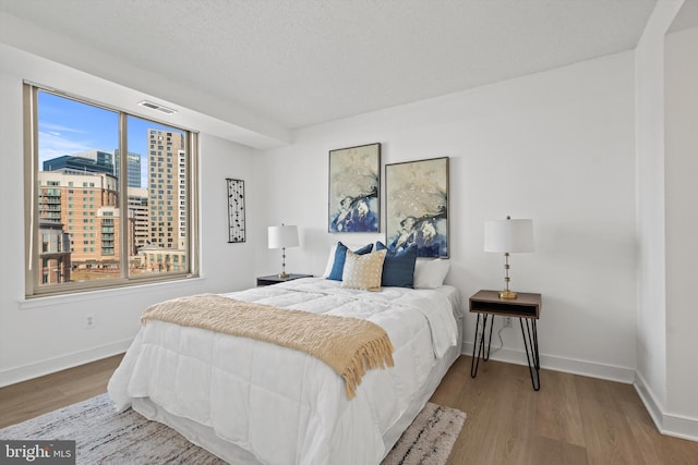 bedroom with multiple windows and hardwood / wood-style flooring