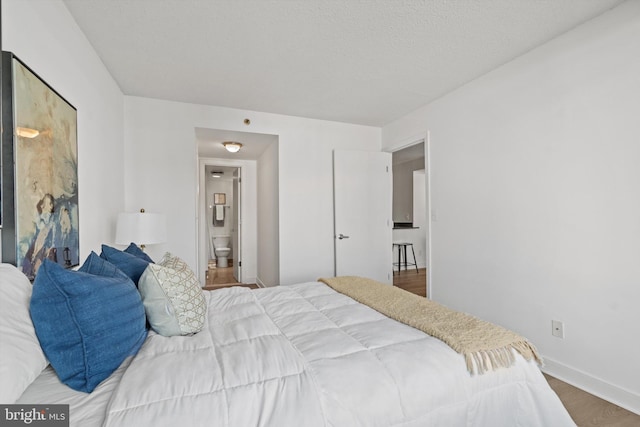 bedroom with connected bathroom and hardwood / wood-style flooring