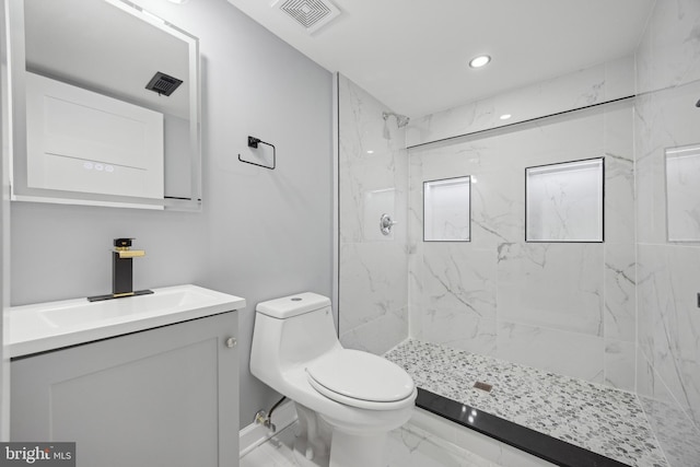 bathroom featuring toilet, vanity, and tiled shower